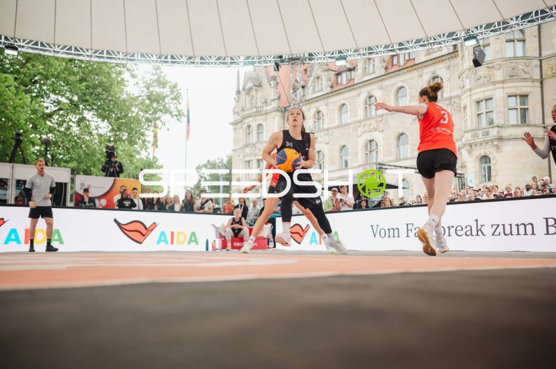 3x3-Basketball-Spielerin mit Ball im Angriff vor historischer Kulisse