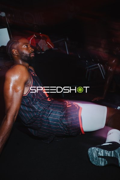 Basketballspieler in dunklem Trikot sitzt nachdenklich auf dem Boden