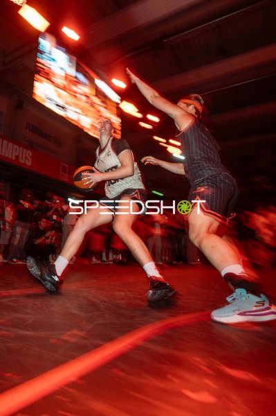 Basketballspielerin mit Ball im Zweikampf unter rotem Hallenlicht in Ulm