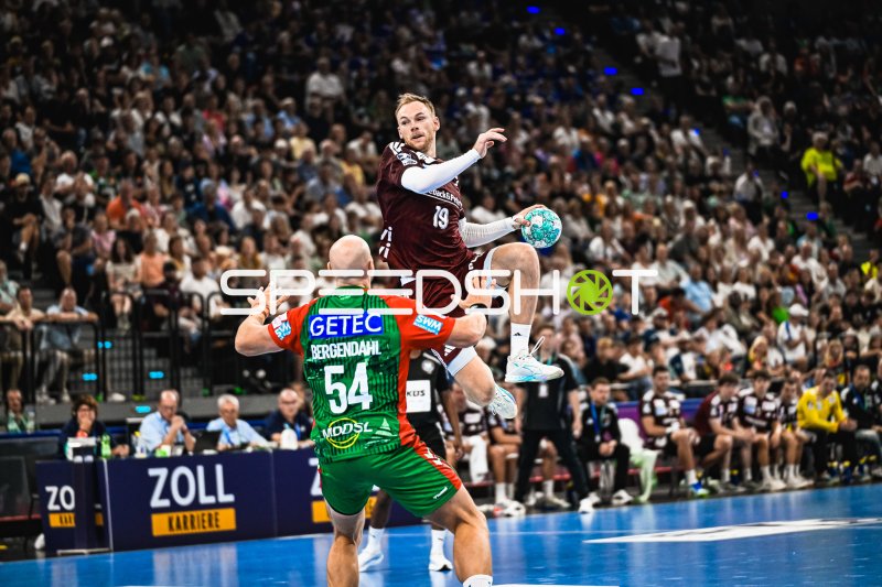 Mathias Gidsel (#19; Füchse Berlin) springt über Oscar Bergendahl (#54; SC Magdeburg)