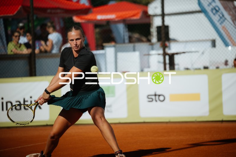 Tennisspielerin beim beidhändigen Rückhand-Schlag auf Sandplatz