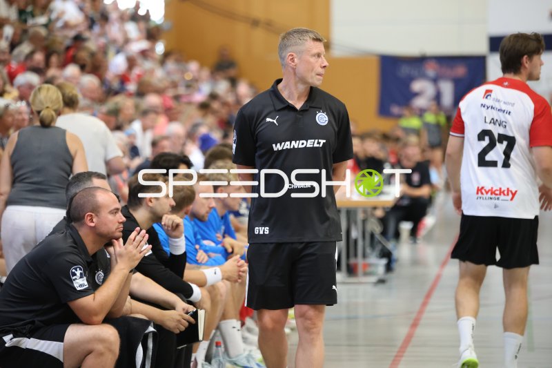 Trainer an der Seitenlinie mit Spieler #27 im Hintergrund