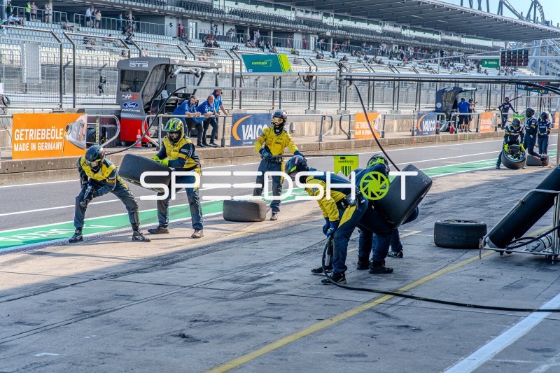 Boxenstopp-Training im Nürburgring Fahrerlager – Mechaniker üben Reifenwechsel