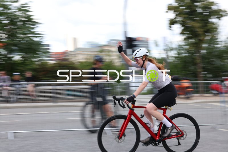 Radfahrerin winkt beim Cyclassics-Rennen in Hamburg