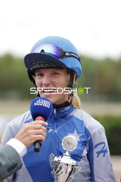 Jockeyfahrerin nach dem Rennen mit Pokal beim Interview