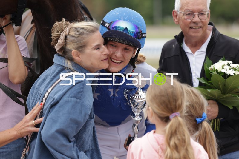Jubelnde Jockeyín mit Pokal nach Siegerehrung auf der Rennbahn Berlin Mariendorf