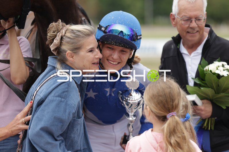 Siegerjubel: Jockey mit Pokal und Familie nach dem Rennen