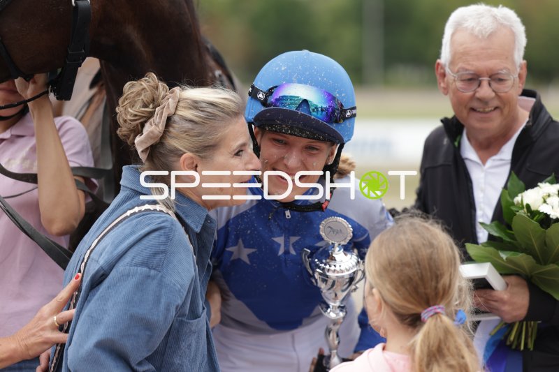 Jockey bei Siegerehrung mit Pokal und Glückwünschen