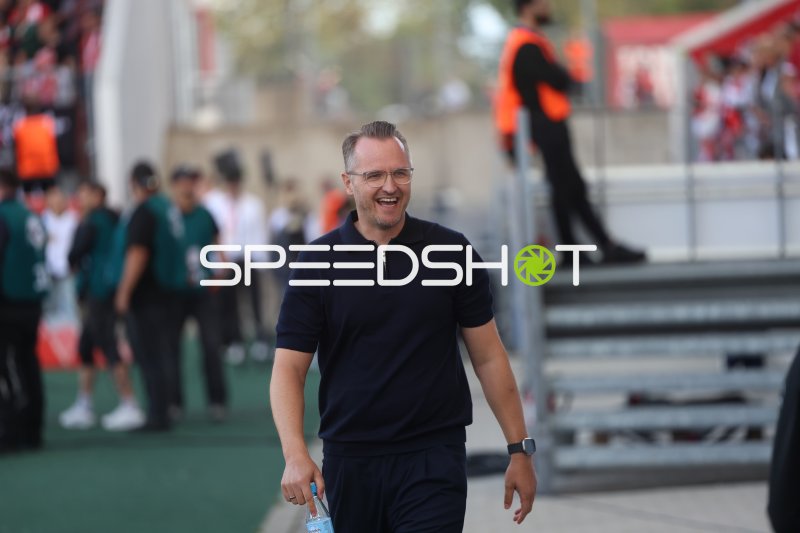 Lächelnder Mann im dunklen Poloshirt am Stadionrand