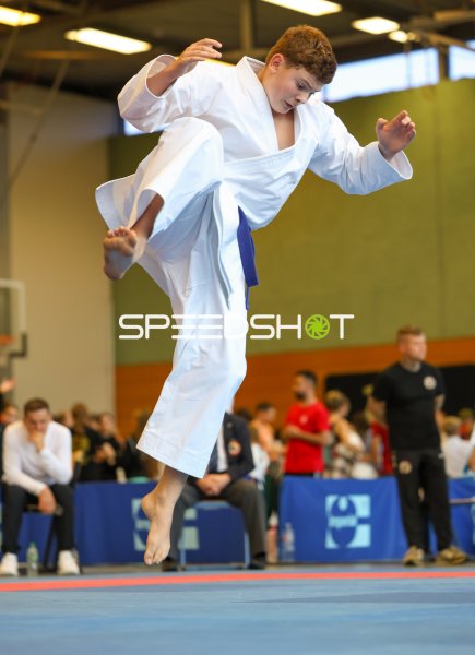 Karateka mit blauem Gürtel beim Sprung in der Kata-Vorführung
