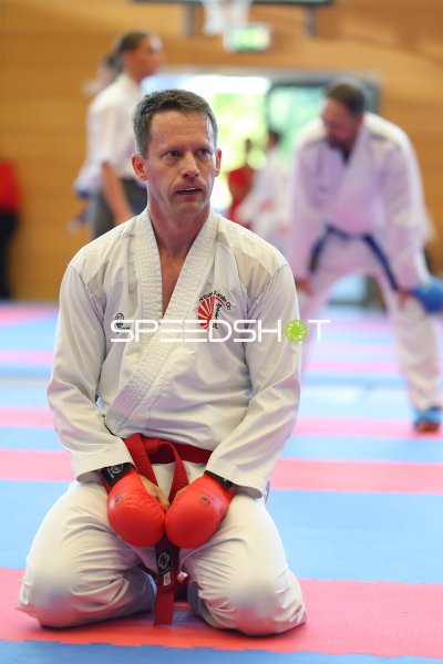 Karateka im weißen Gi kniet konzentriert auf der Wettkampffläche in Eckernförde