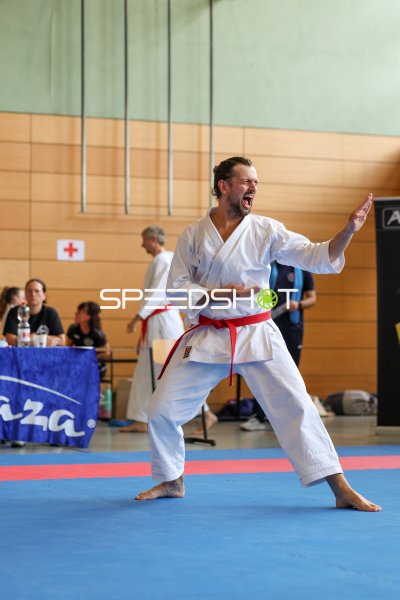 Karateka mit rotem Gürtel führt Kata-Technik mit Kiai aus