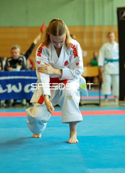 Karateka in tiefer Kata-Position auf blauer Wettkampffläche in Eckernförde