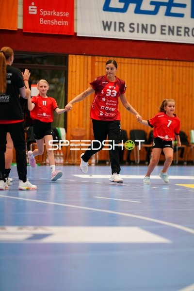 Lucie-Marie Kretzschmar (#33; HSG Bensheim/Auerbach) läuft mit Kindern aufs Spielfeld