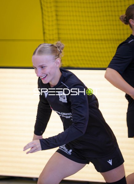 Handballspielerin in Abwehrhaltung lächelt während des Aufwärmens