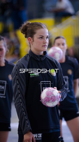 Handballerin in Aufwärmjacke mit Ball vor dem Spiel