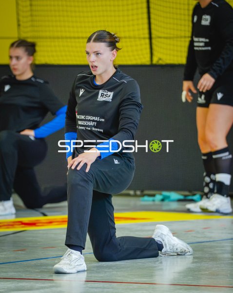 Handballerinnen beim Aufwärmen und Dehnen in der Halle
