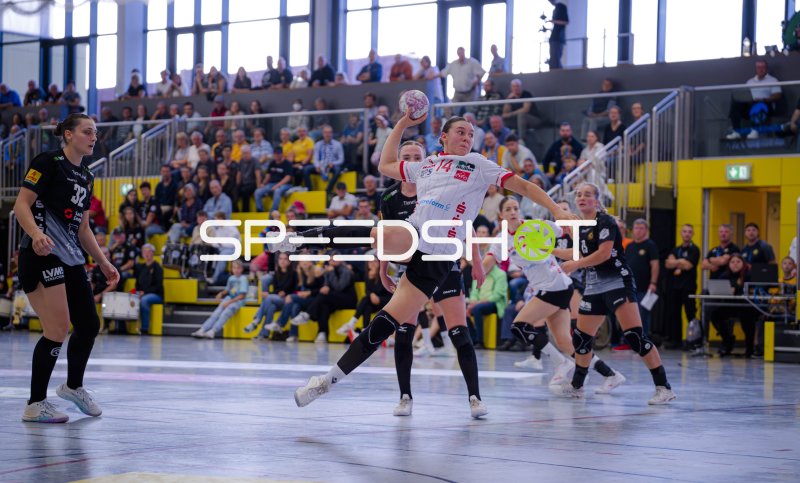 Handballerin (#14) springt zum Wurf über die Abwehr