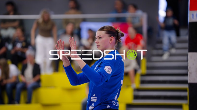 Handballspielerin im blauen Trikot signalisiert mit erhobenen Händen
