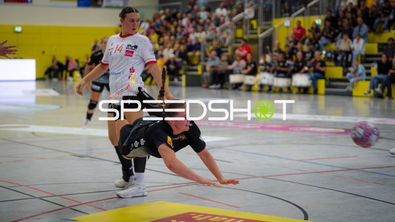Handballerin im Hechtwurf gegen Torhüterin im weißen Trikot mit Nummer 14