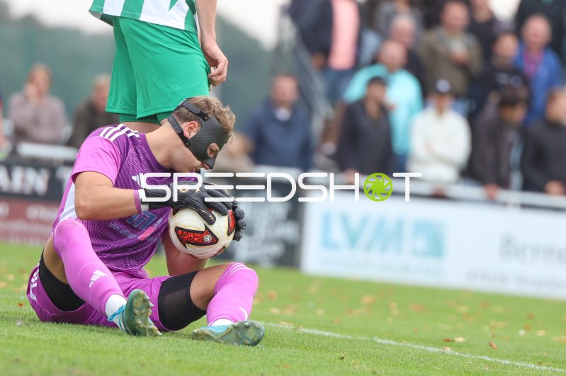 Torwart in Magenta-Trikot sichert Ball am Boden