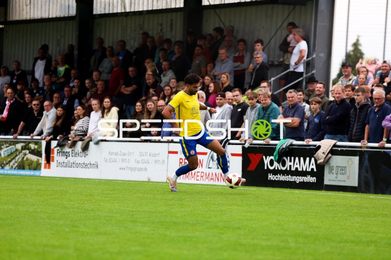 Spieler in Gelb-Blau mit Ball im Laufduell an der Seitenlinie