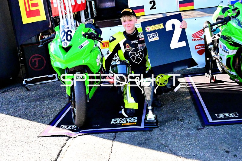 Motorrad-Rennfahrer mit Pokal und Kawasaki Ninja in der Siegerehrung