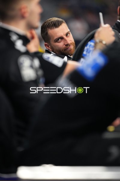 Lukas Mertens (#22; SC Magdeburg) blickt auf der Bank in die Kamera