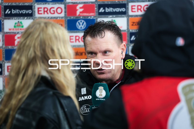 Uwe Koschinat im Interview vor der Sponsorenwand