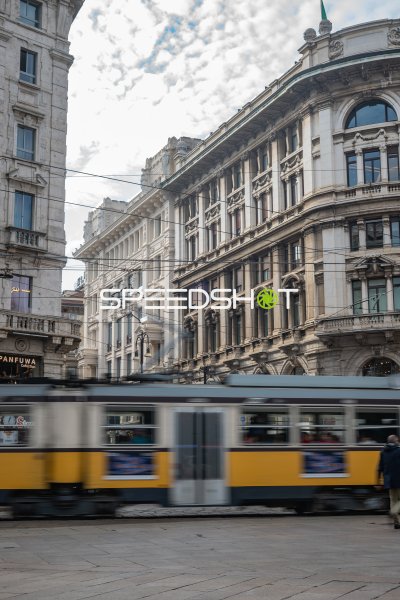 Gelbe Straßenbahn in Bewegungsunschärfe vor historischer Fassade