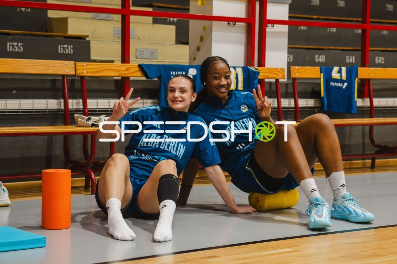 Zwei Frauen im ALBA-Berlin-Shirt zeigen Victory-Zeichen auf dem Hallenboden