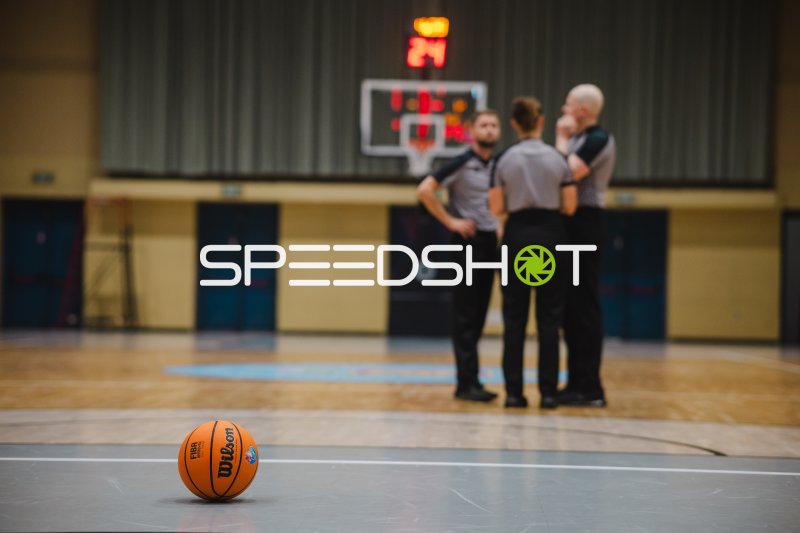Schiedsrichter besprechen sich vor dem Korb, Basketball im Vordergrund
