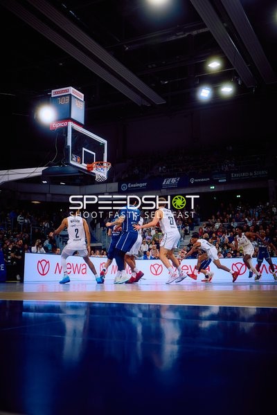 Spieler mit der Nummer 11 von Brose Bamberg dribbelt den Ball in Richtung Korb, verteidigt von mehreren Spielern der MLP Academics Heidelberg.