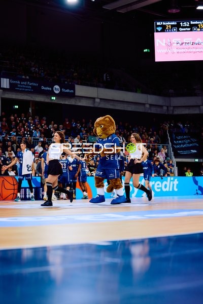 Maskottchen performt auf dem Spielfeld mit Tänzerinnen