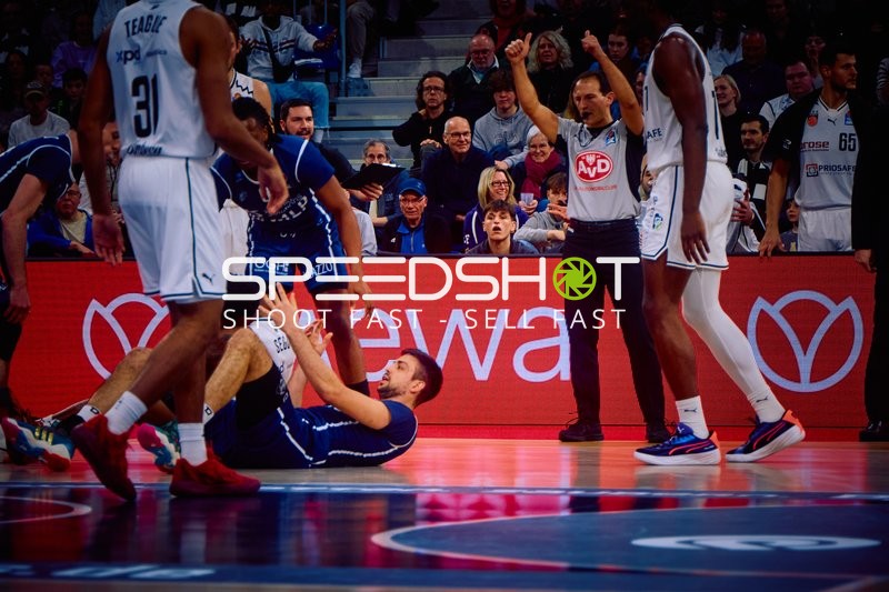 Ein Spieler von Brose Bamberg liegt auf dem Boden, während andere Spieler um ihn herum stehen.