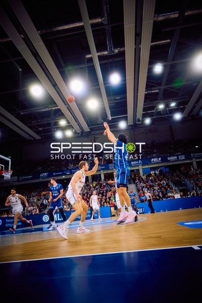 Ein Spieler von Brose Bamberg wirft einen Ball, während ein Gegenspieler versucht zu blocken.