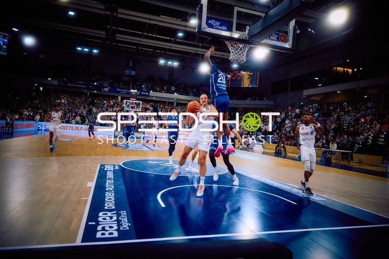 Ein Spieler von MLP Academics Heidelberg versucht einen Korbleger, während ein Spieler von Brose Bamberg einen Block versucht.