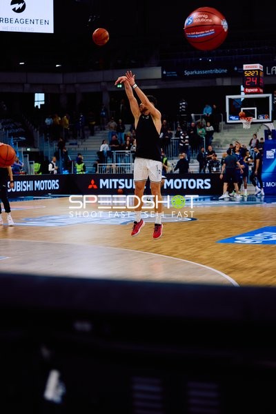 Ein Basketballspieler macht einen Sprungwurf in der Halle.