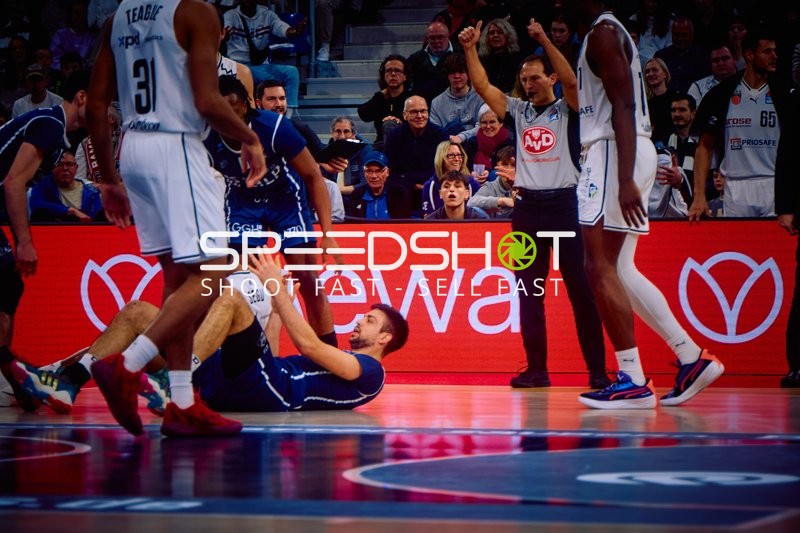 Ein Spieler von Brose Bamberg hilft einem am Boden liegenden Mitspieler auf.