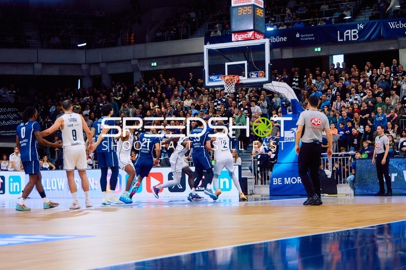 Ein heimischer Spieler versucht, den Ball in den Korb zu werfen, während der Gegner verteidigt.