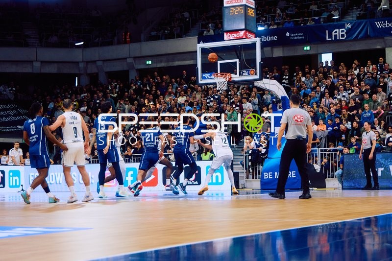 Ein Spieler von MLP Academics Heidelberg versucht einen Korb zu werfen, während Spieler von Brose Bamberg verteidigen.