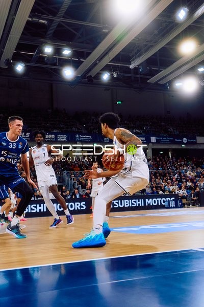 Ein Spieler von Brose Bamberg dribbelt den Ball, während MLP Academics Spieler verteidigen.
