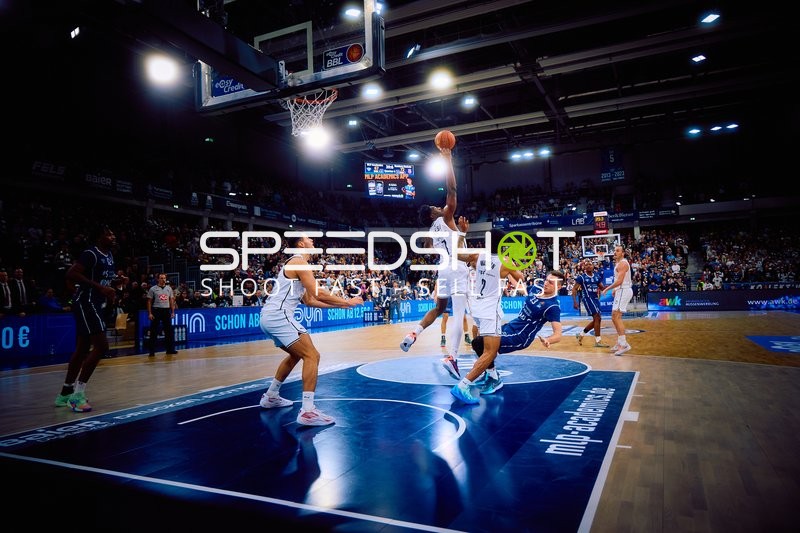 Ein Spieler der MLP Academics Heidelberg springt zum Korbwurf, während ein Spieler von Brose Bamberg versucht zu blocken.