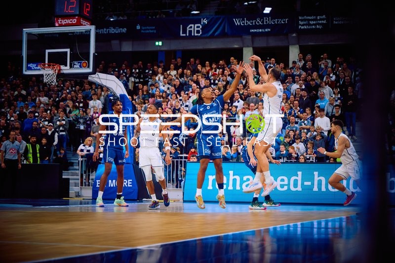 Ein Spieler von Brose Bamberg versucht einen Wurf, während Spieler der MLP Academics Heidelberg verteidigen.