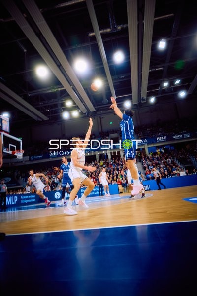 Ein Spieler von Brose Bamberg wirft einen Korb, während ein Spieler von MLP Academics Heidelberg verteidigt.
