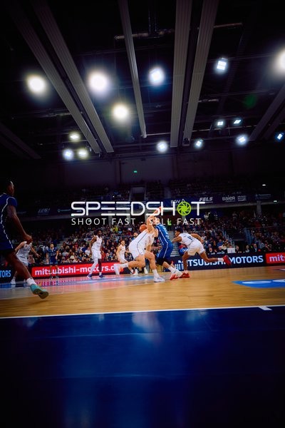 Ein Spieler in blau versucht, einen Pass unter Druck von Gegnern in weiß zu machen.