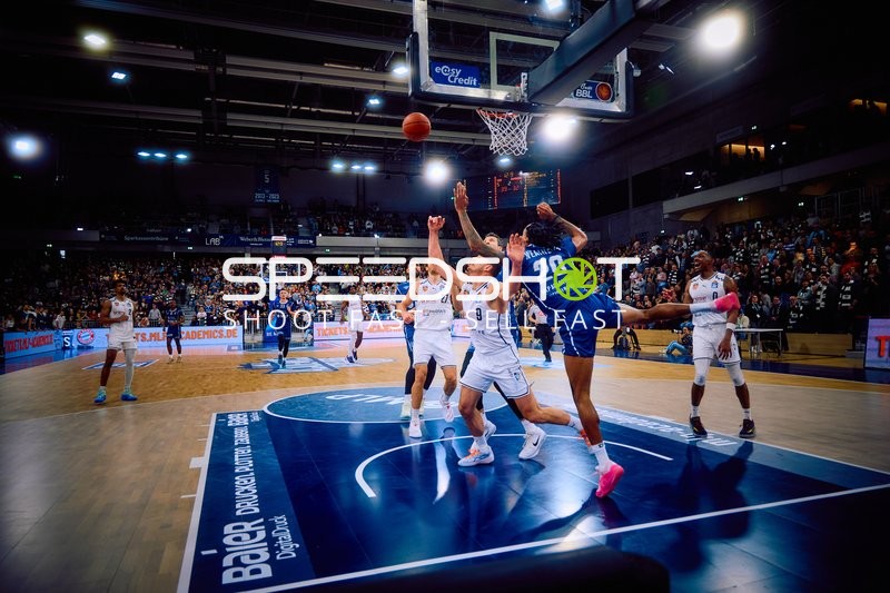 Ein Spieler von MLP Academics Heidelberg versucht, einen Korb zu werfen, während ein Spieler der Brose Bamberg verteidigt.