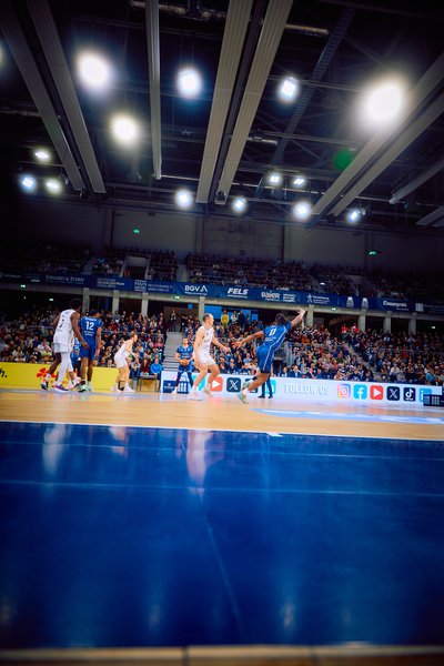 Ein Spieler von Brose Bamberg dribbelt den Ball nach vorne, während ein Spieler der MLP Academics Heidelberg verteidigt.