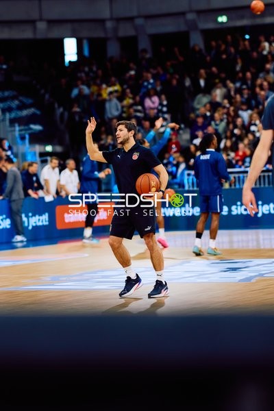 Ein Spieler von Brose Bamberg wärmt sich mit einem Ball auf dem Spielfeld auf.