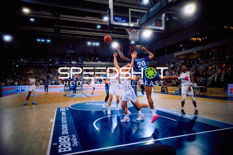 Ein Spieler von Brose Bamberg versucht, einen Korbleger zu erzielen, während mehrere Spieler von MLP Academics Heidelberg verteidigen.